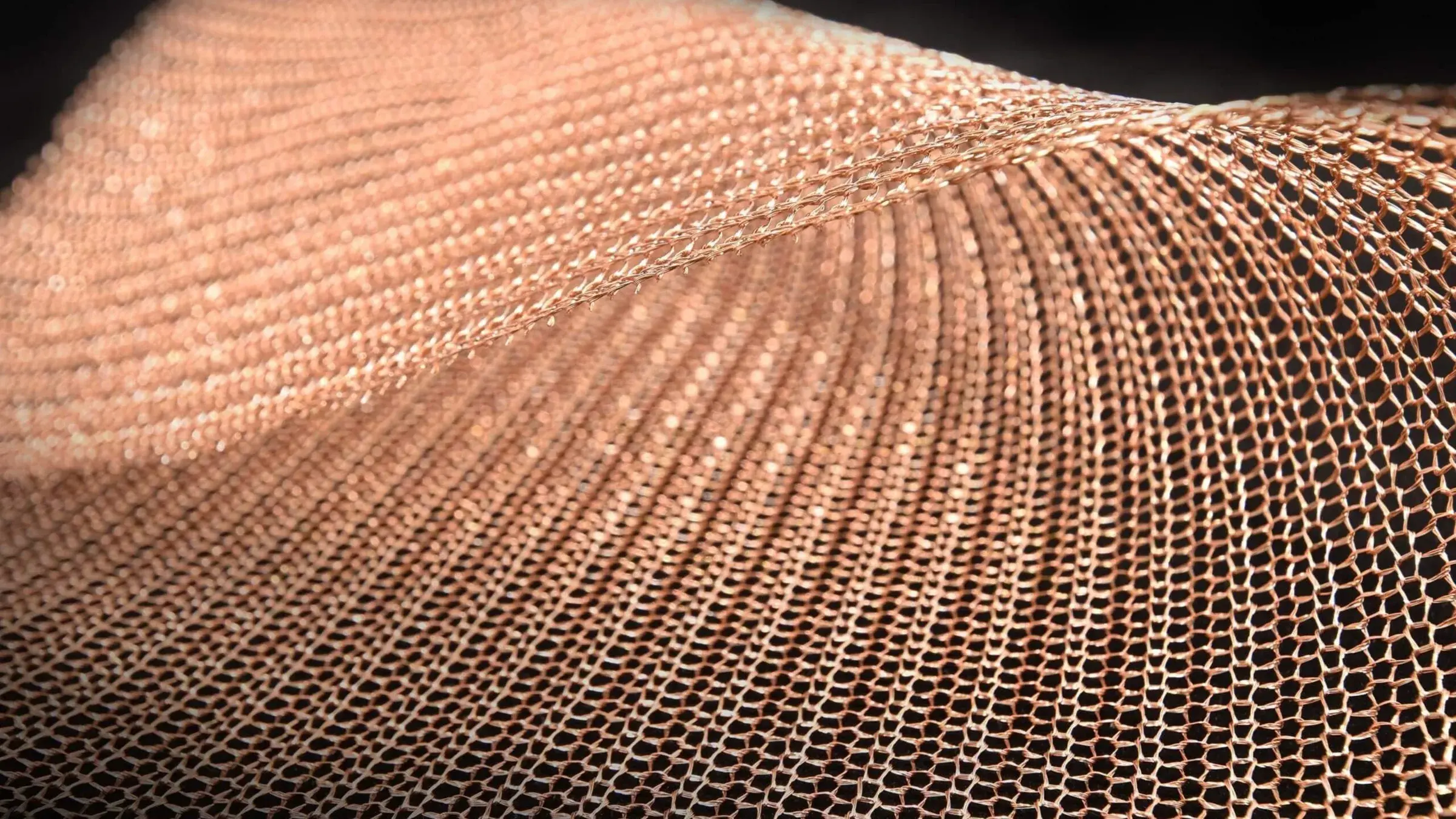 Close-up of copper woven metal mesh rippling across the frame